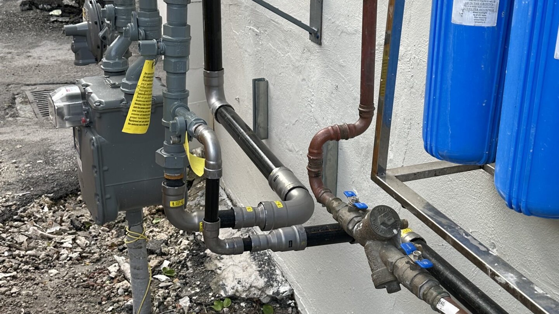 Whole-home blue water filter canisters on exterior stucco