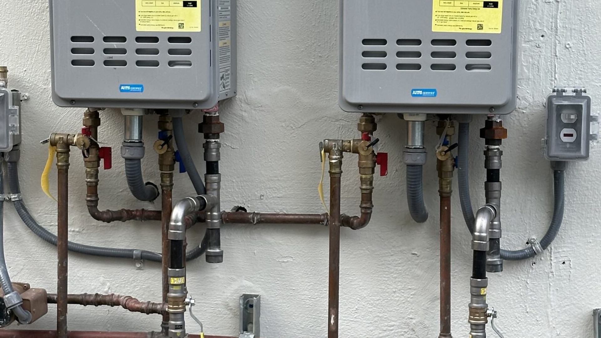 Dual outdoor tankless water heaters mounted on Miami stucco